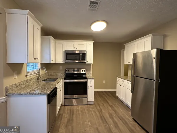 a kitchen with a refrigerator a stove top oven a sink and dishwasher with wooden floor