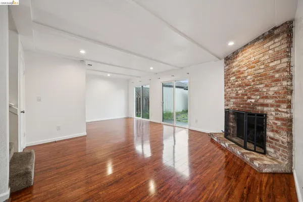 a view of an empty room with wooden floor fireplace and a window