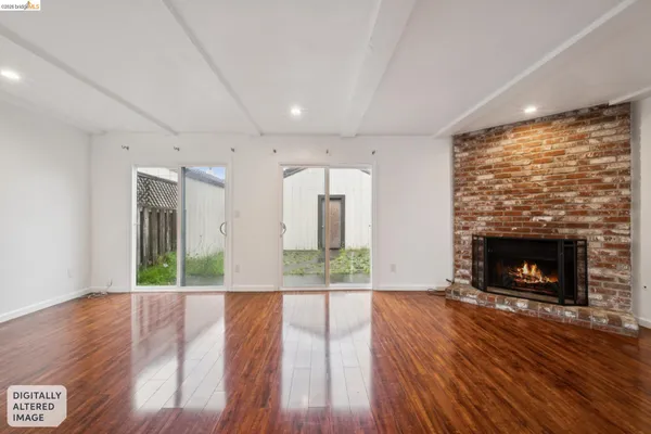 an empty room with wooden floor fireplace and windows