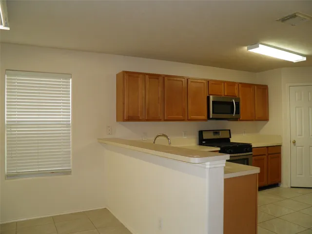 a kitchen with stainless steel appliances granite countertop a stove a sink a microwave and a refrigerator