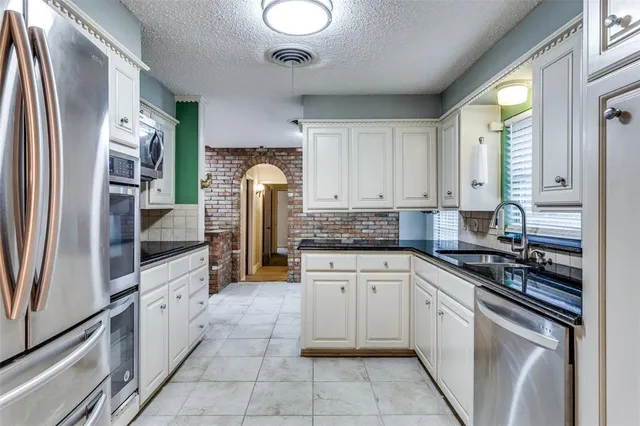 a kitchen with white cabinets and appliances