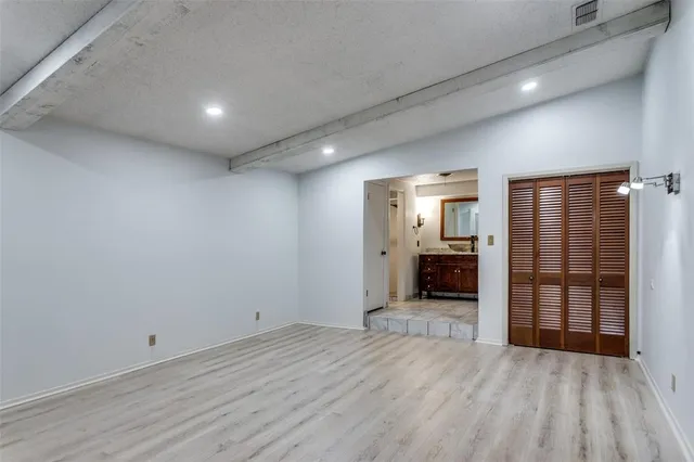 an empty room with wooden floor fireplace and windows