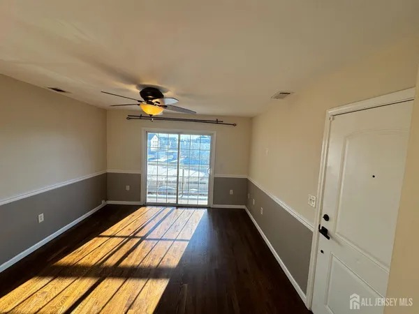 a view of empty room with wooden floor and fan