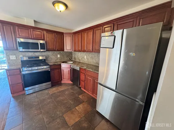 a kitchen with stainless steel appliances granite countertop a refrigerator a stove a sink dishwasher and wooden cabinets