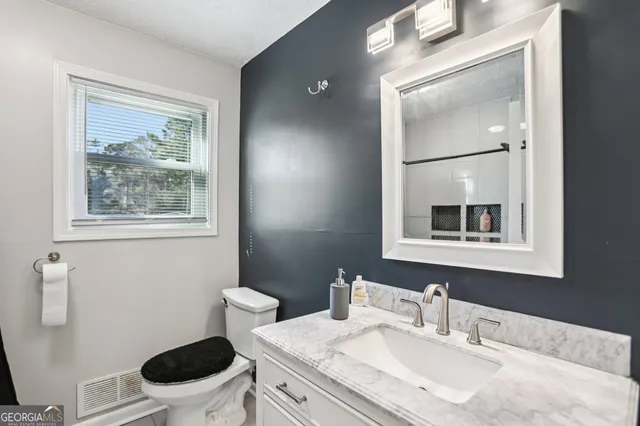 a bathroom with a granite countertop toilet a sink and mirror