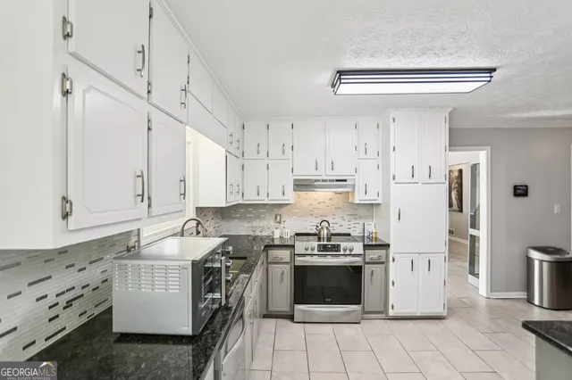 a kitchen with stainless steel appliances a stove a refrigerator and white cabinets
