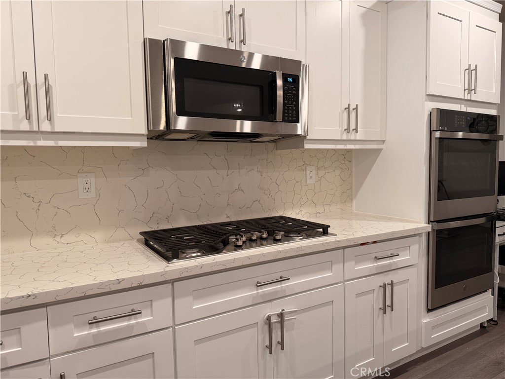 562 Hudson Way Rialto, CA 92377 - Photo 3 of 5 a kitchen with white cabinets and black appliances