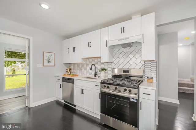 a kitchen with stainless steel appliances white cabinets and a stove top oven