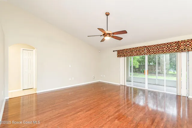 a view of an empty room with wooden floor and a window