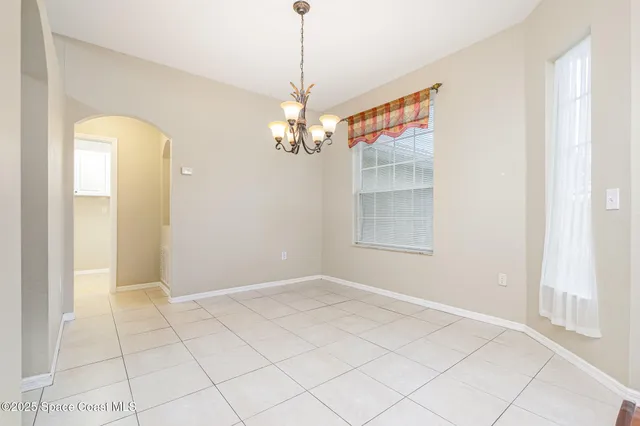 a view of a livingroom with a chandelier fan and kitchen view