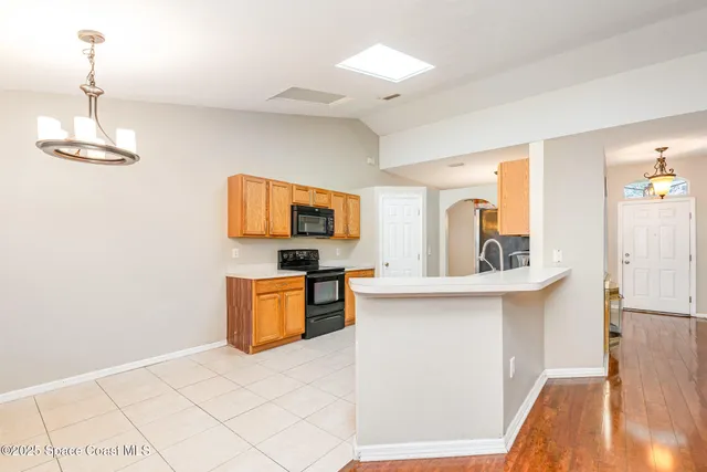 a kitchen with stainless steel appliances a stove top oven a sink a microwave a dining table and chairs with wooden floor