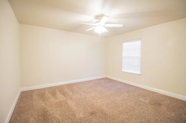 an empty room with a window and a fan