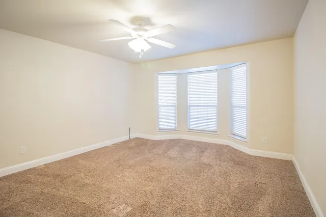 an empty room with windows and chandelier fan