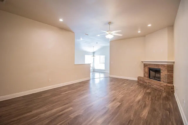 an empty room with wooden floor fireplace and windows