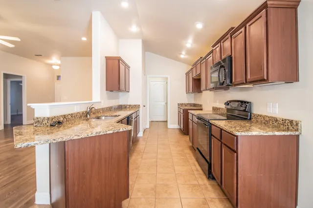 a kitchen with stainless steel appliances granite countertop a sink stove and cabinets
