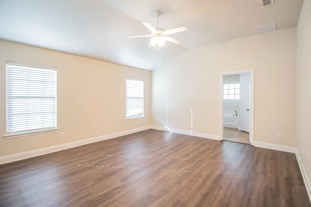 an empty room with wooden floor and windows