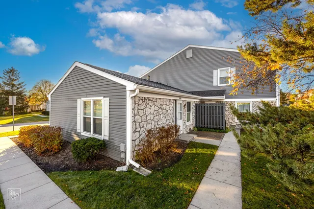 a view of a house with a small yard and a large tree