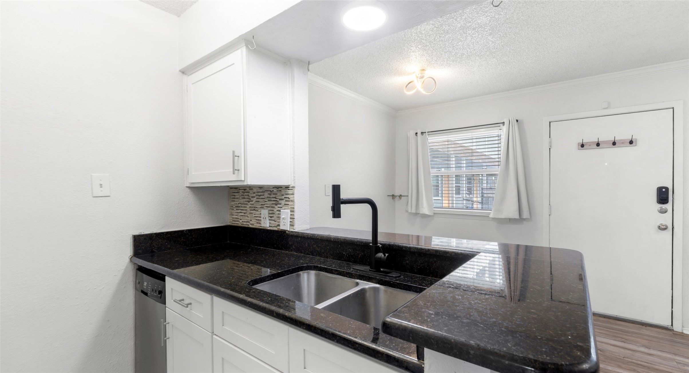 2401 Manor Road, Unit 123 Austin, TX 78722 - Photo 8 of 22 A well-appointed kitchen features dark granite countertops, modern cabinetry, and a double-basin sink with contemporary black fixtures.