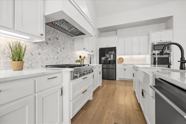 a kitchen with white cabinets a sink dishwasher and a stove with wooden floor
