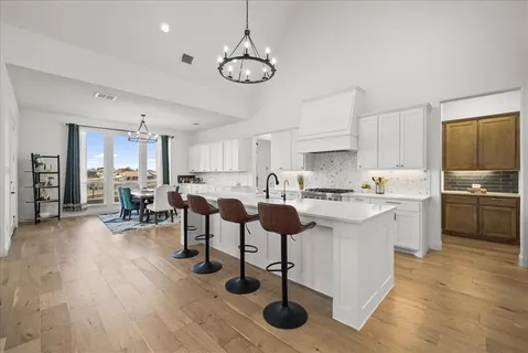 a kitchen with stainless steel appliances a stove a sink dishwasher a oven cabinets and a dining table with wooden floor