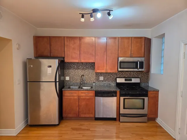 a kitchen with a refrigerator a stove top oven a sink and dishwasher with wooden floor