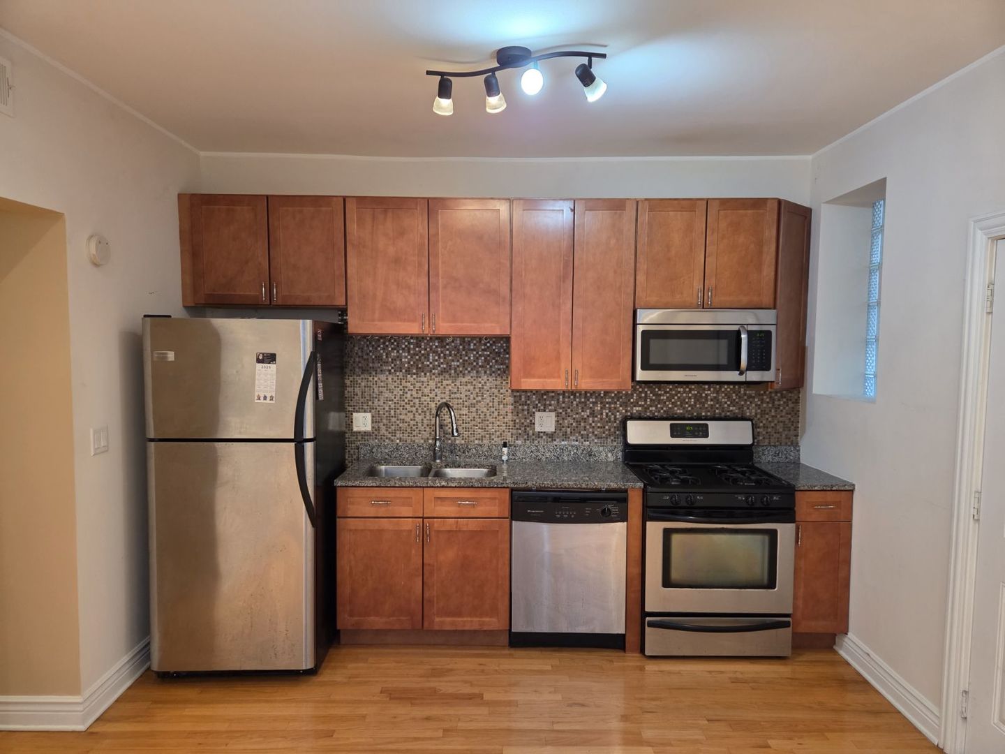 5902 West Madison Street, Unit 3 Chicago, IL 60644 - Photo 14 of 18 a kitchen with a refrigerator a stove top oven a sink and dishwasher with wooden floor
