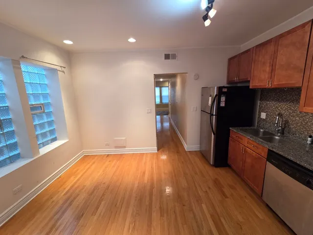 a kitchen with stainless steel appliances a refrigerator and wooden floor