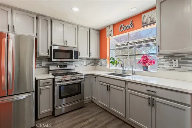 a kitchen with stainless steel appliances a sink cabinets and a window