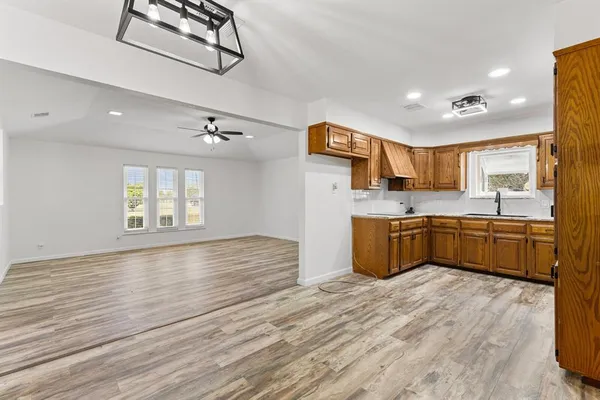 a large kitchen with stainless steel appliances granite countertop a sink dishwasher a stove and a refrigerator with wooden floor