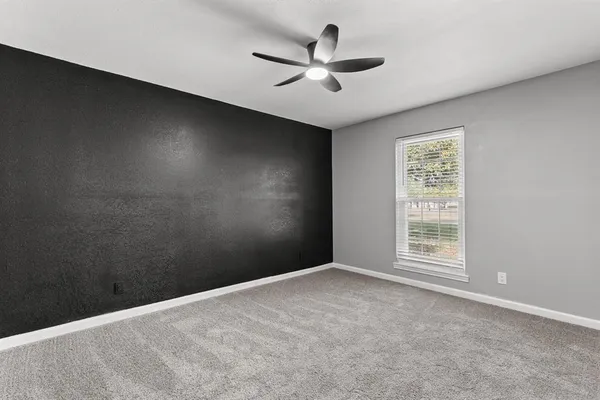 an empty room with a window and a fan