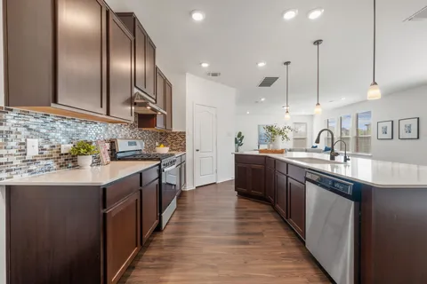 a large kitchen with stainless steel appliances a sink and a wooden floor