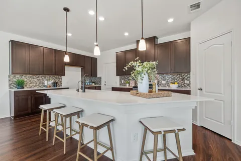 a kitchen with kitchen island a stove a table and chairs in it