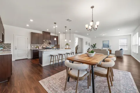 a view of a dining room and livingroom with furniture wooden floor a chandelier