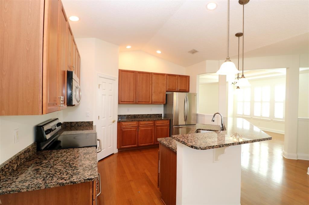 207 Sunset Point St. Augustine, FL 32080 - Photo 29 of 59 a kitchen with kitchen island granite countertop a stove a sink a refrigerator and a granite counter tops