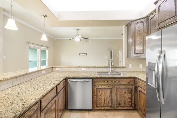 a kitchen with granite countertop a sink and refrigerator