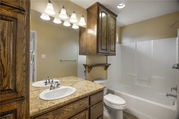 a bathroom with a granite countertop sink toilet and a mirror