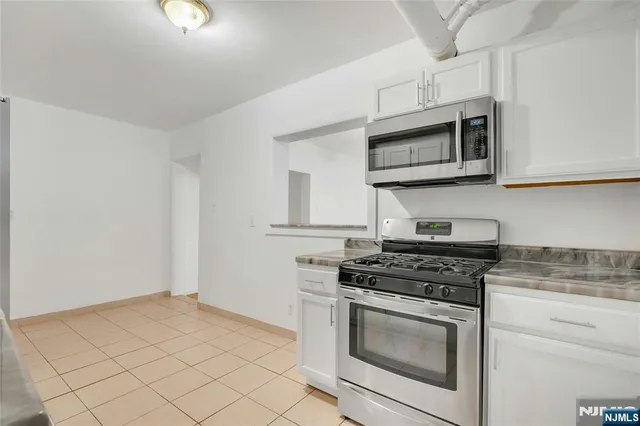 a kitchen with stainless steel appliances granite countertop white cabinets a stove top oven