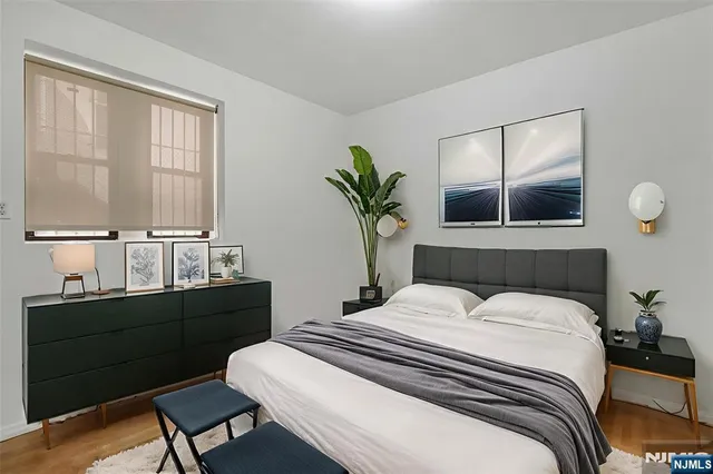 a bedroom with a bed table chair and window