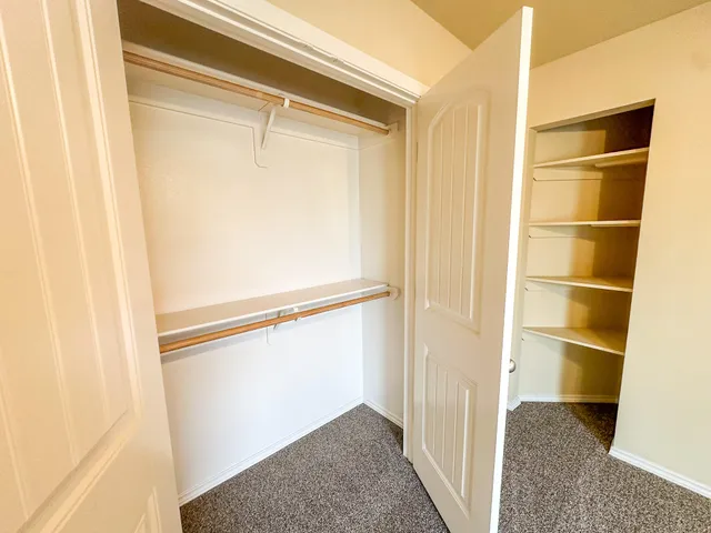 an empty room with closet and a ceiling fan