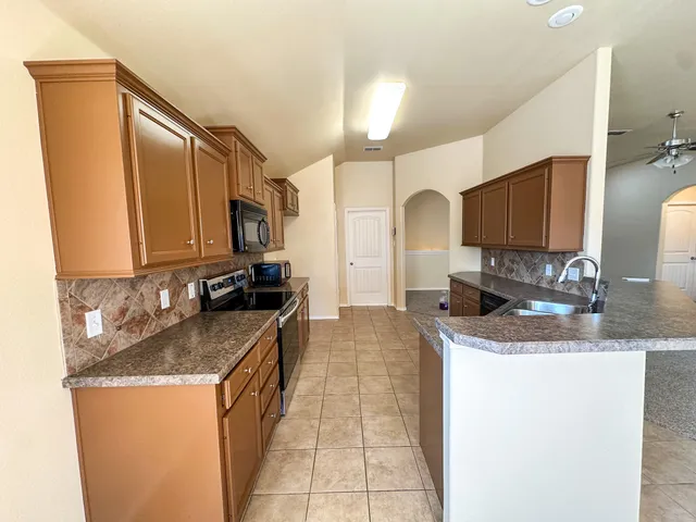 a kitchen with granite countertop a sink a stove counter space and cabinets