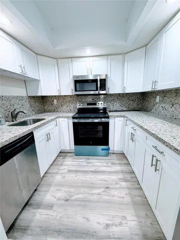 a kitchen with stainless steel appliances granite countertop a stove top oven a sink dishwasher and a refrigerator