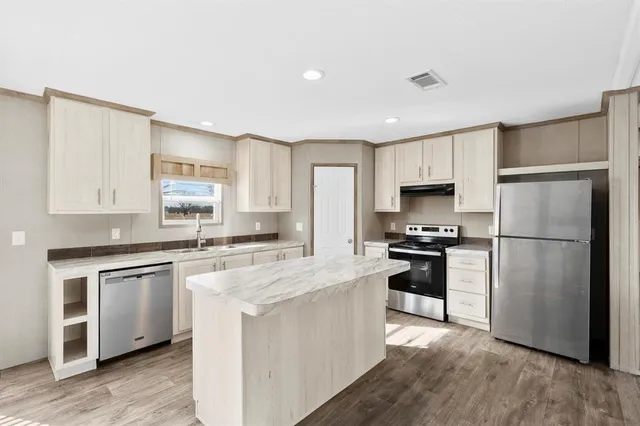 a kitchen with cabinets stainless steel appliances and a window
