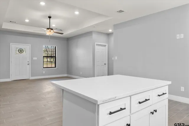 a kitchen with a refrigerator a ceiling fan and wooden floor