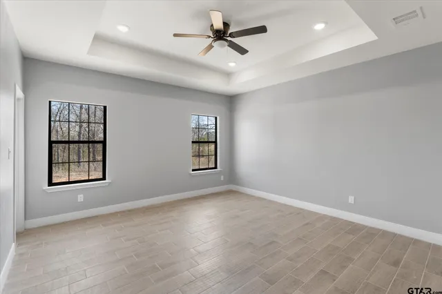 an empty room with windows and ceiling fan