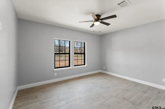 an empty room with window and ceiling fan