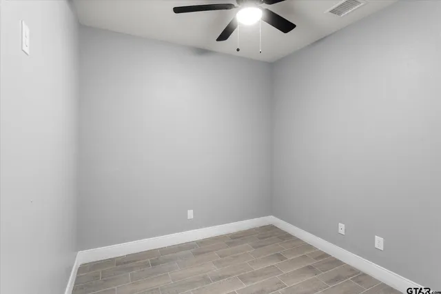 an empty room with a chandelier fan and windows