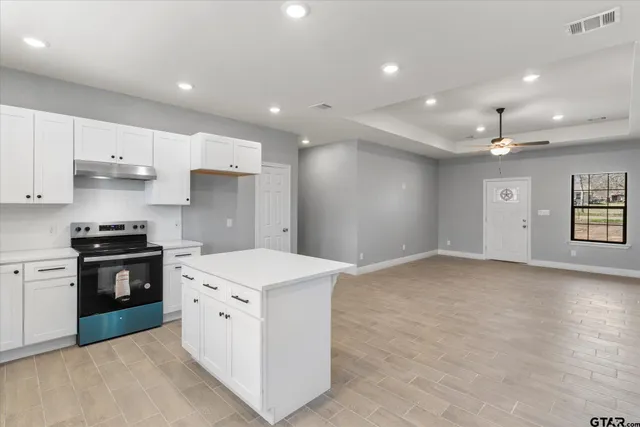 a kitchen with stainless steel appliances kitchen island granite countertop a sink a stove a refrigerator and a stove