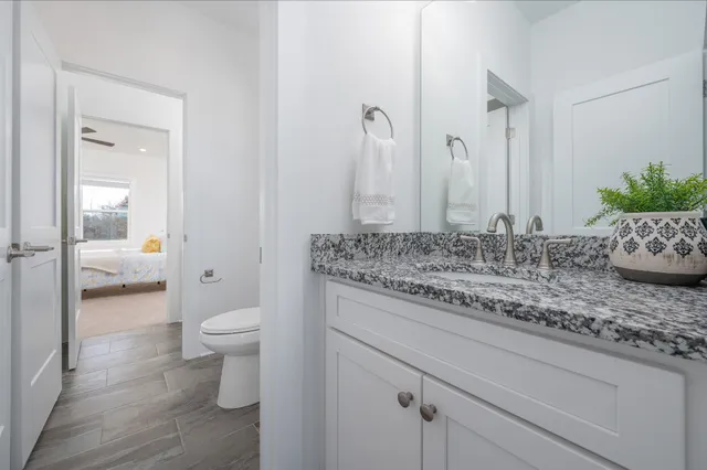 a bathroom with a granite countertop sink a toilet and shower