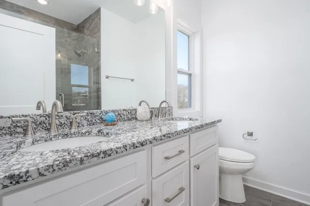 a bathroom with a granite countertop sink and a toilet