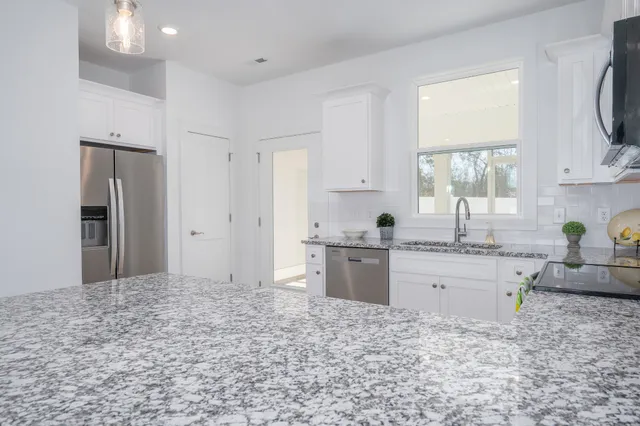 a kitchen with granite countertop a sink stainless steel appliances and cabinets